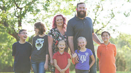 A foster family standing outside smiling for a family photo.